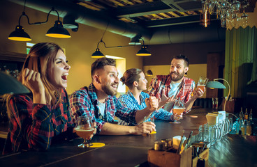 Sport, people, leisure, friendship and entertainment concept - happy football fans or male friends drinking beer and celebrating victory at bar or pub