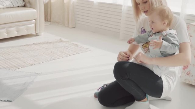 Young mother put on shoes to her lovely baby. Happy family. Slow motion