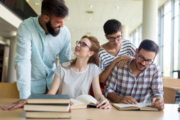 Young happy students sitting in library