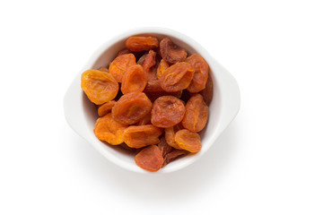 orange dried apricots close up in a white bowl on a white background