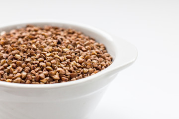 buckwheat groats in a white bowl on a white background close up