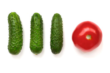 three green cucumbers and a red tomato on a white background