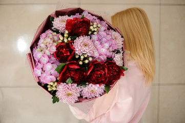 Rear view girl holding a beautiful bright bouquet of pink and red flowers