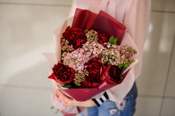 Girl holding a beautiful bouquet of bright red and rose colour flowers