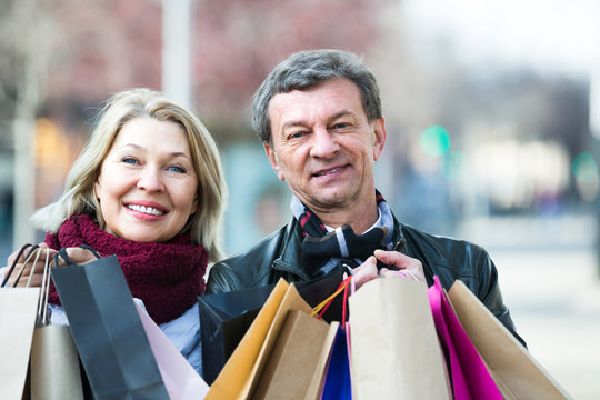 Mature spouses with shopping bags outdoor.