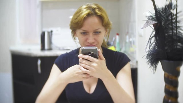woman is eating pizza in the kitchen at home and using her smartphone, 4k, background blur