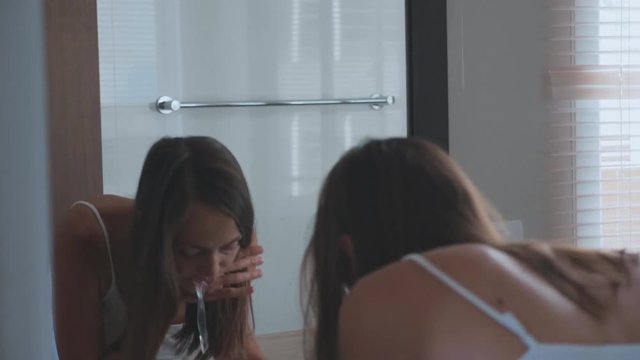 Young woman brushing teeth with a tooth brush in bathroom