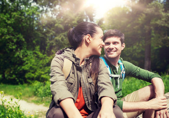 travel, hiking, backpacking, tourism and people concept - smiling couple with backpacks resting and talking in nature