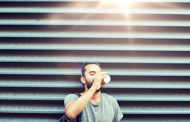 people, drinks, leisure and lifestyle - man drinking coffee from disposable paper cup on city street