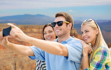 travel and tourism concept - group of happy friends taking selfie by cell phone over grand canyon national park background