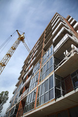A modern new building. Working crane on the construction of the house. Construction site with cranes on sky background. 