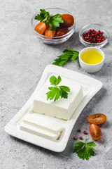 Feta cheese on plate with tomatoes, herbs, olive oil and spices. Selective focus, space for text. 
