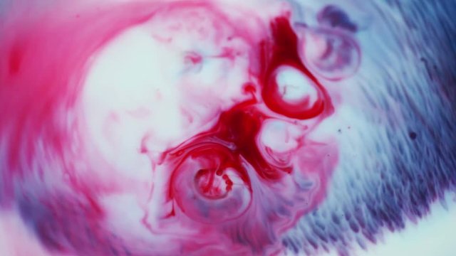 Dark red and blue paints spread out and blend from central sources 