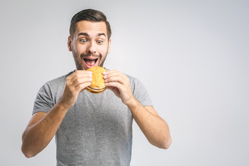 Young man holding a piece of hamburger. Student eats fast food. Burger is not helpful food. Very...
