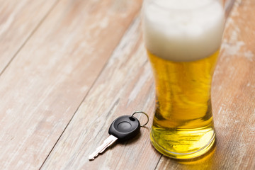 alcohol abuse, drunk driving and people concept - close up of beer in glass and car key on table