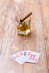 gambling, fortune and entertainment concept - glass of whisky and playing cards on table