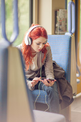 young beautiful woman listening to music in a train, subway, urban mood concept