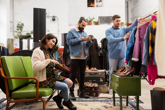 sale, shopping, fashion and people concept - friends choosing clothes and footwear at vintage clothing store
