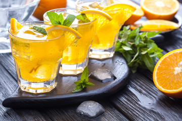 orange cocktail with ice and fresh mint on a black wooden table