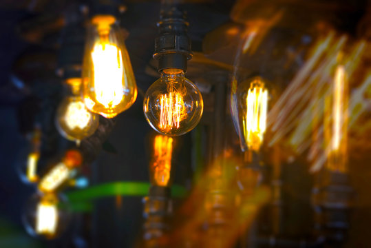Vintage glowing light bulb lamp hanging. Interior decoration in old style luxury design. Focus on the foreground light.