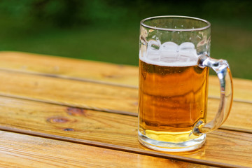 Pint of beer on the wooden table in te garden