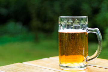 Pint of beer on the wooden table in te garden