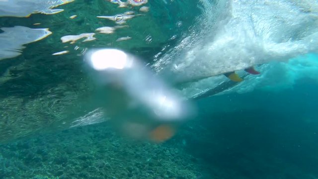 SLOW MOTION, UNDERWATER: Cool surfer girl riding big barrel waves near popular surf spot in sunny Fiji. Athletic woman on active summer holiday surfs an epic Cloudbreak wave. Perfect summer activity.