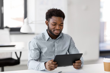 business, people and technology concept - african american businessman with tablet pc computer at office