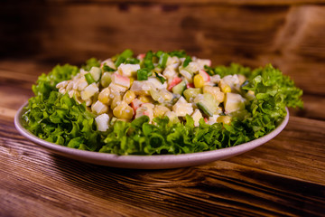 Ceramic plate with salad from crab sticks on wooden table