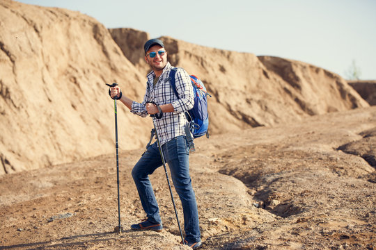 Photo of smiling tourist man with walking sticks on hill