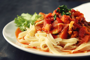 Ribbon pasta with Arrabiata sauce. Close up. Mediterranean dish. Tagliolini pasta with vegetables. Cauliflower, courgette and tomato stew. Italian cuisine. Vegan and vegetarian.
