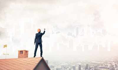 Man architect draw silhouette of modern city on blue sky. Mixed 