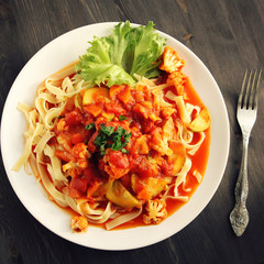 Ribbon pasta with Arrabiata sauce. Close up. Mediterranean dish. Tagliolini pasta with vegetables. Cauliflower, courgette and tomato stew. Italian cuisine. Vegan and vegetarian. Top view. Toned photo.