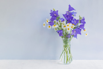 Summer blue flowers in a vase on a light blue background