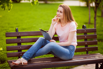 Fototapeta premium Pensive girl with tablet sitting on the bench
