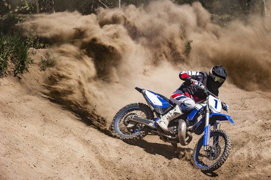 Motocross rider creates a large cloud of dust and debris