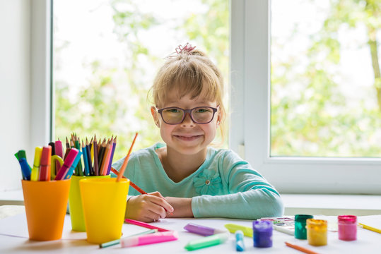 Cute Little Girl Doing Homework, Reading A Book, Coloring Pages, Writing And Painting. Children Paint. Kids Draw. Preschooler With Books At Home. Preschoolers Learn To Write And Read. Creative Toddler