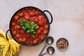 Meatballs in rich tomato sauce in cast iron pot. Top view, blank space