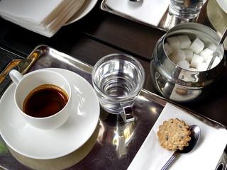 A cup of coffee, a glass of water, a sugar bowl on a tray