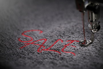 embroidery of red lettering SALE on soft grey fabric with embroidery machine - close up -...