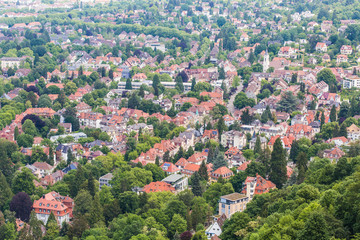 aerial view of a city; red roofs of private houses among green trees