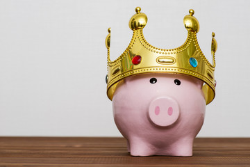 Financial winner or king of money savings concept, smiling happy pink piggy bank wearing a golden...