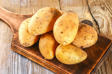 Yellow potato tubers on an old wooden table.