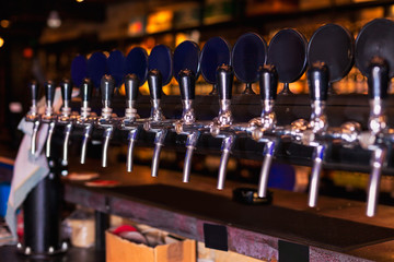 Beer tap row in bar counter - obrazy, fototapety, plakaty