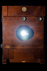 Frontal vintage rare wooden camera projecting light from the inside