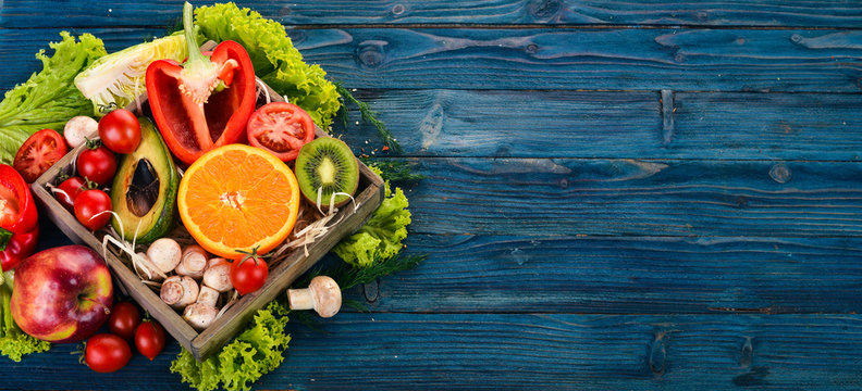 Assortment of fresh vegetables and fruits. Healthy food On a blue wooden background. Top view. Copy space.