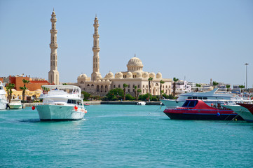 Seascape with motor yachts in marina. View of mosque  in the  background. Hurghada, Egypt - obrazy, fototapety, plakaty