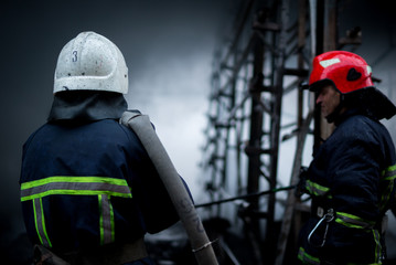 Fototapeta premium Firefighters spray water. Smoke and buiding after fire