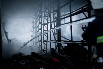 Firefighters spray water. Smoke and buiding after fire