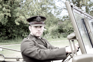 Handsome American WWII GI Army officer in uniform riding Willy Jeep